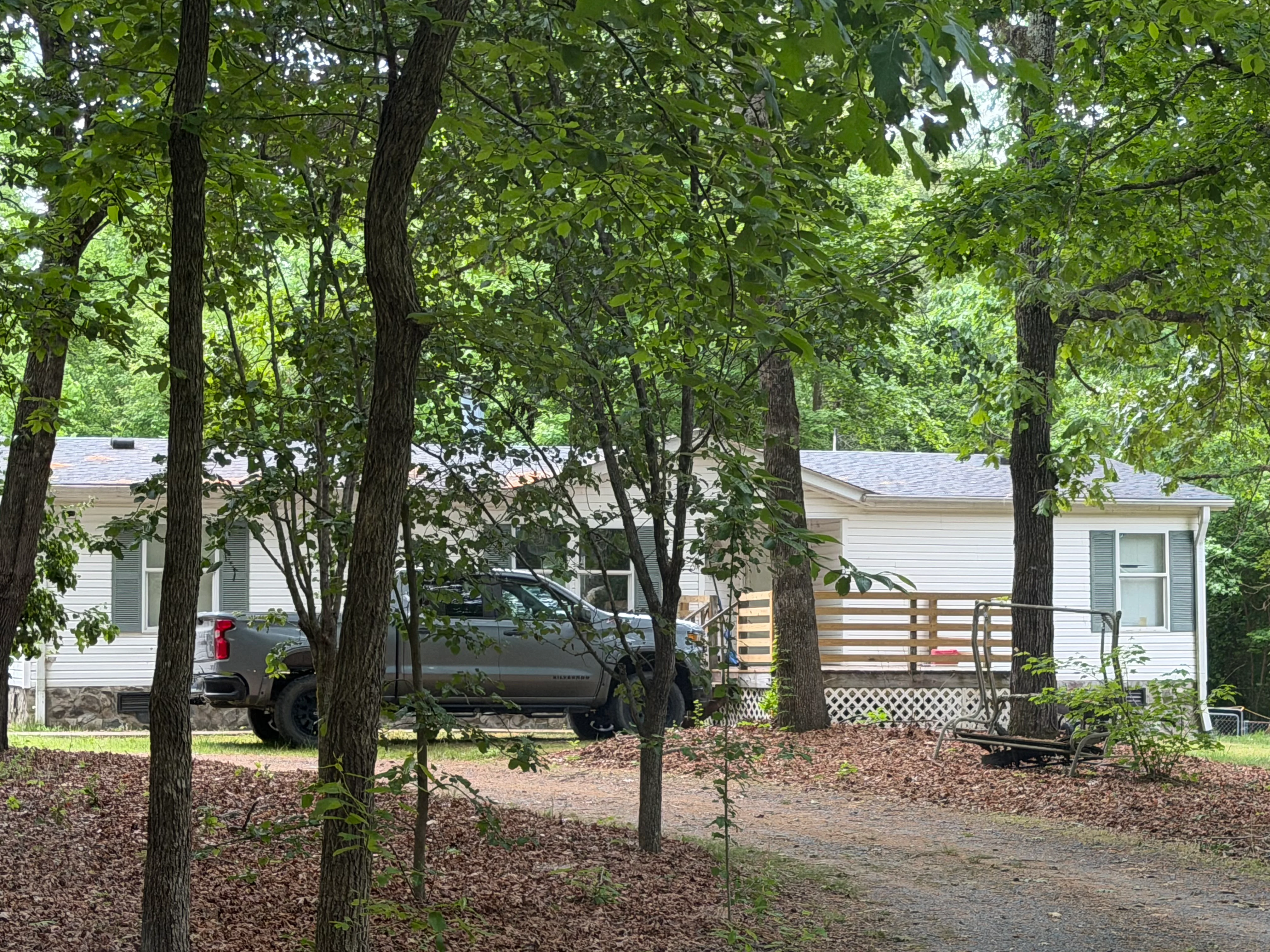 Residential home with mulched crawl space area and wooden deck among tall trees