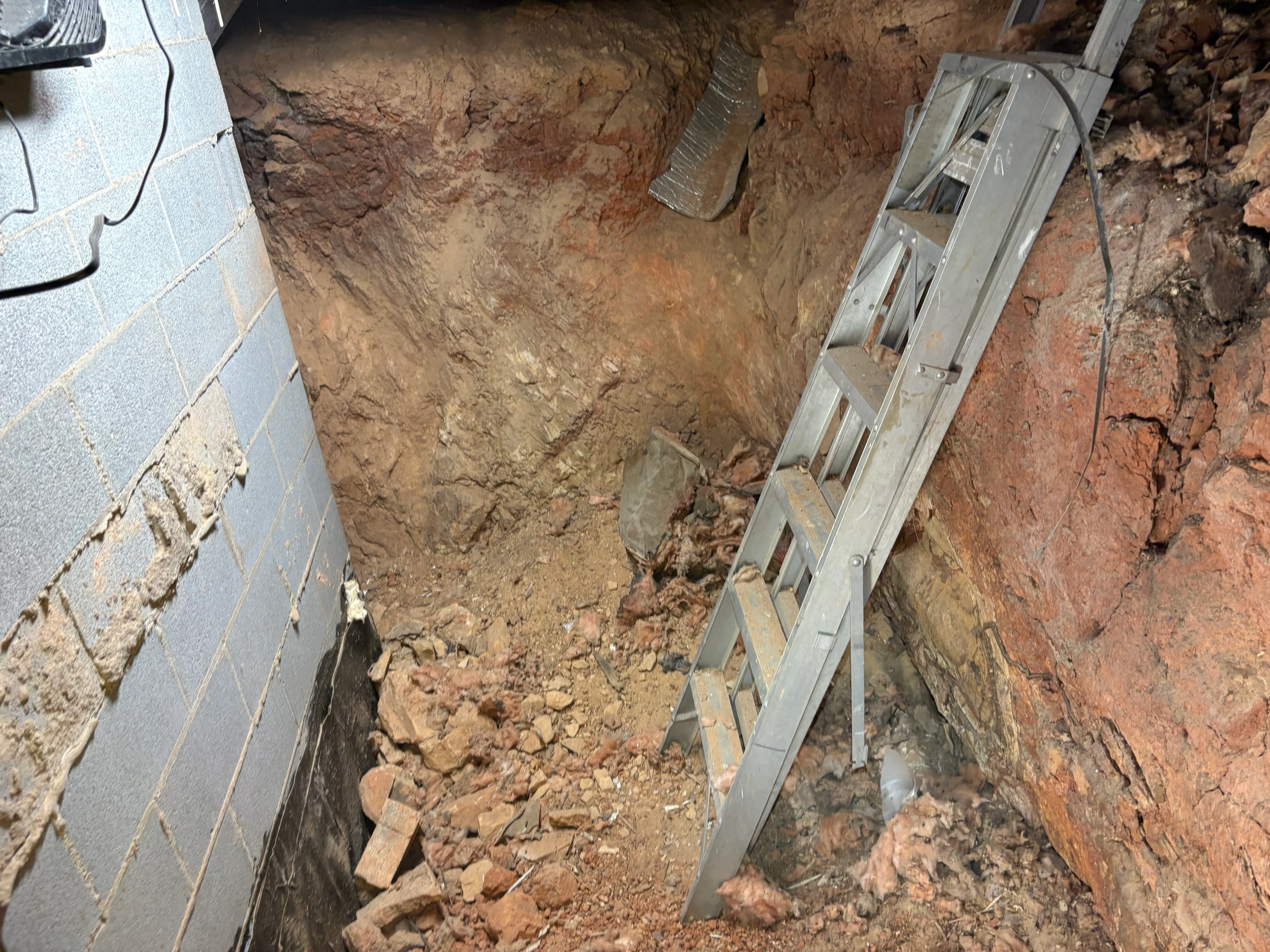 Excavated crawl space with metal support beams and exposed brick foundation walls