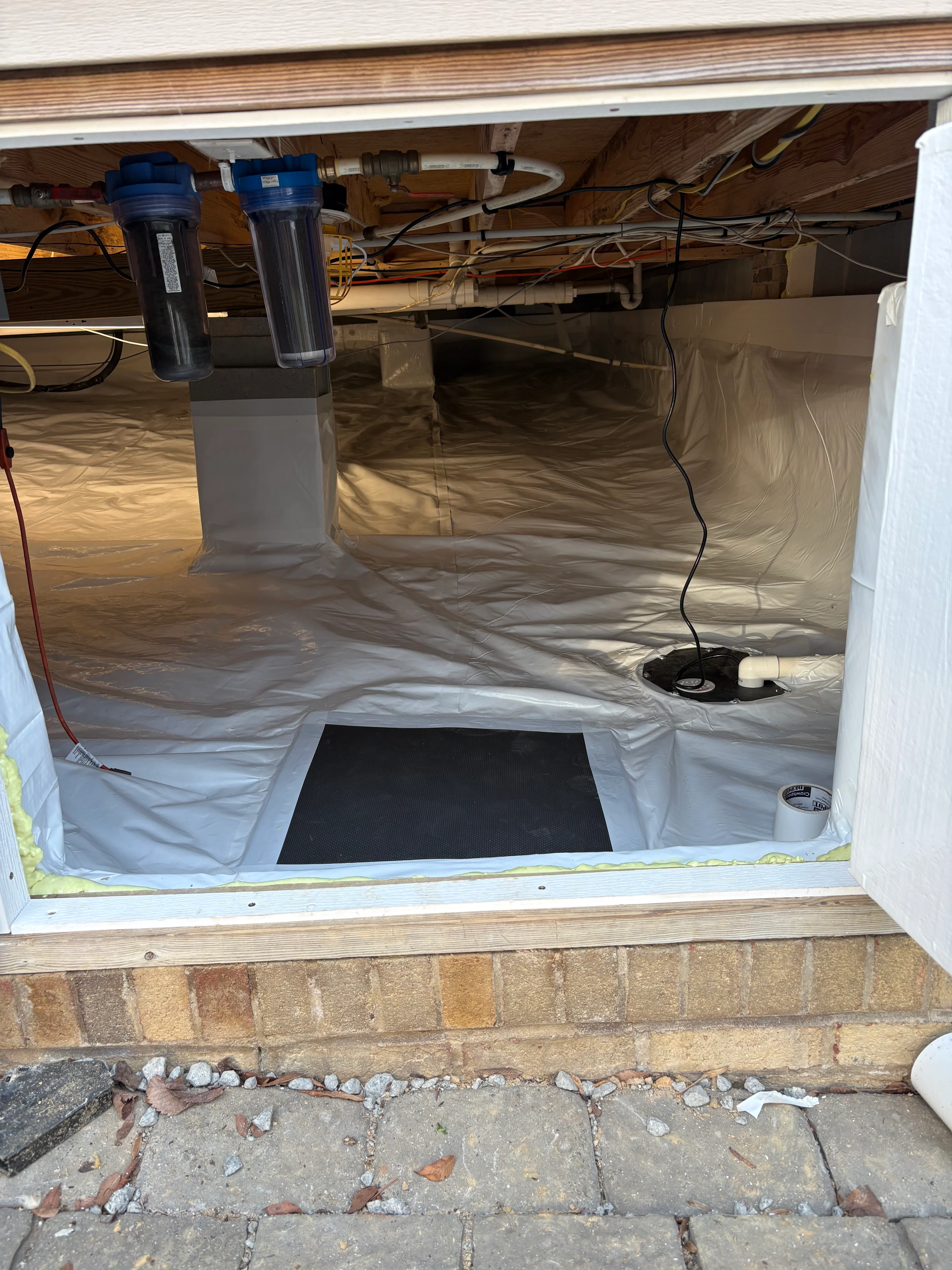 Crawl space with white vapor barrier, dual dehumidifiers, and organized mechanical systems