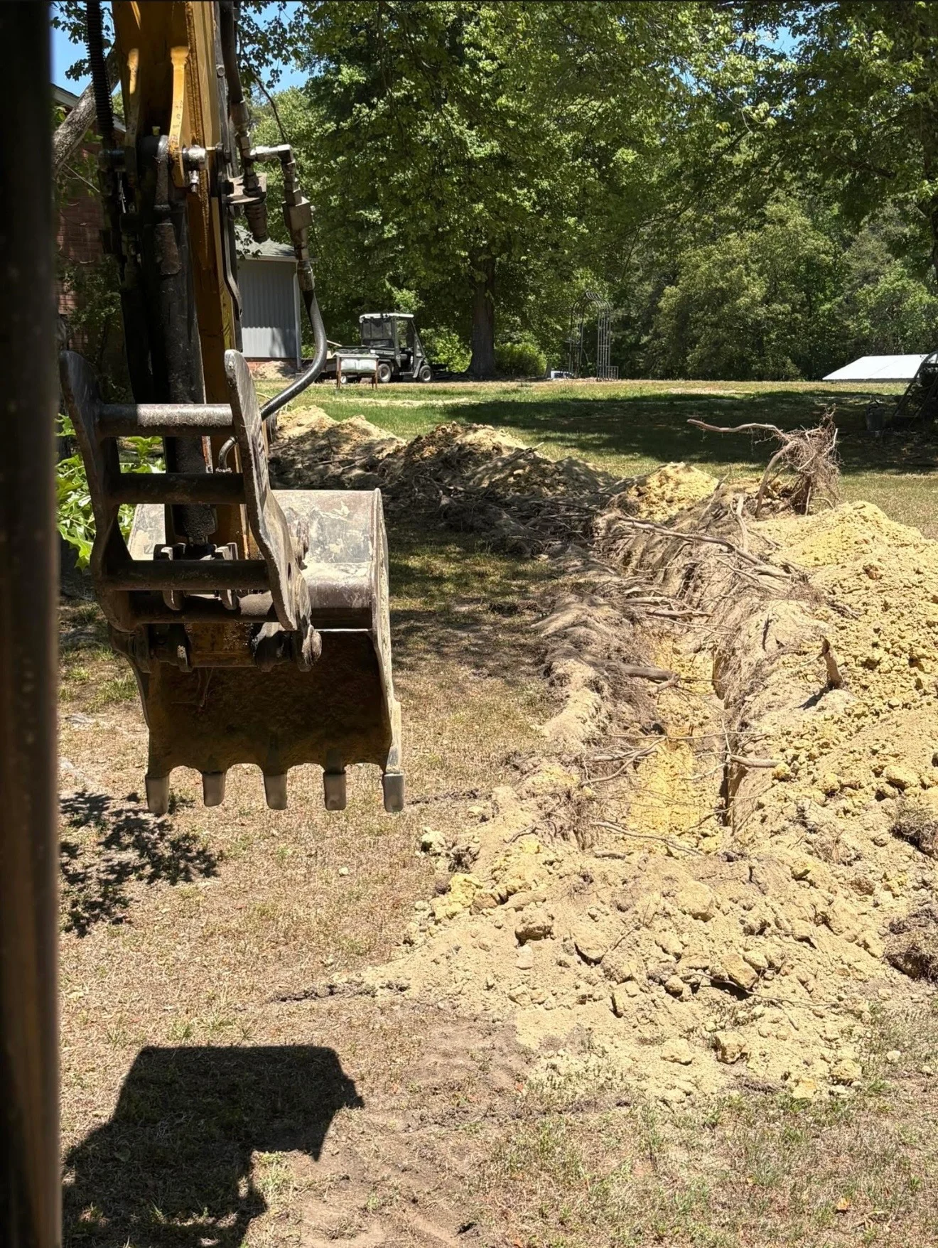 Excavator bucket removing soil during crawl space excavation and site preparation