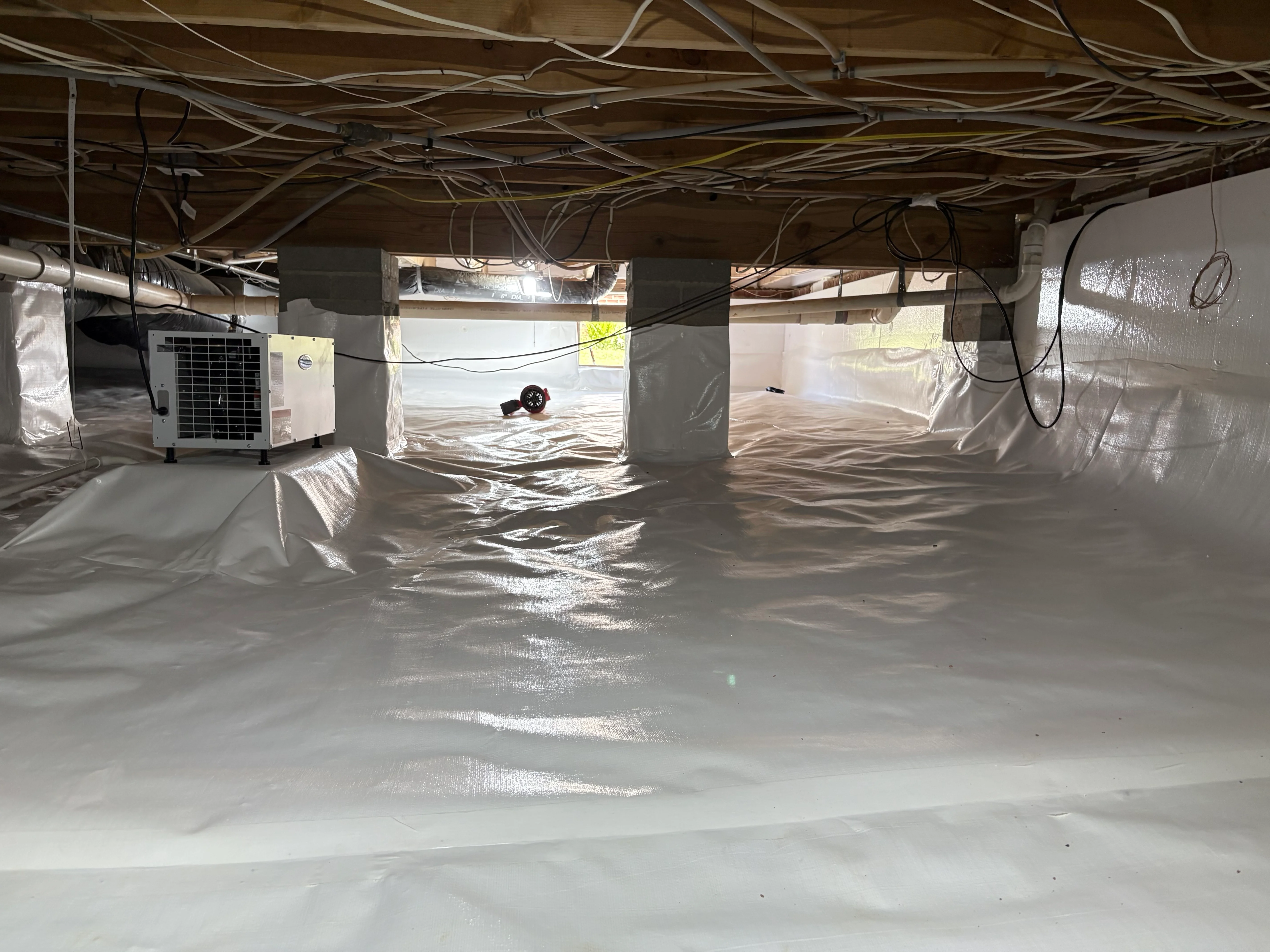 Encapsulated crawl space with vapor barrier, dehumidifier, and HVAC equipment installed